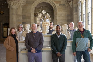 A group of people standing amongst busts